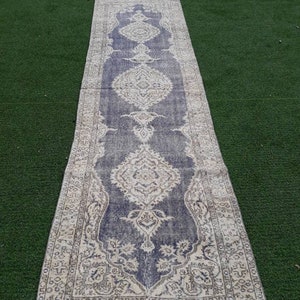 May include: A long, narrow rug with a faded blue and cream color scheme. The rug has a traditional Persian design with intricate floral patterns.