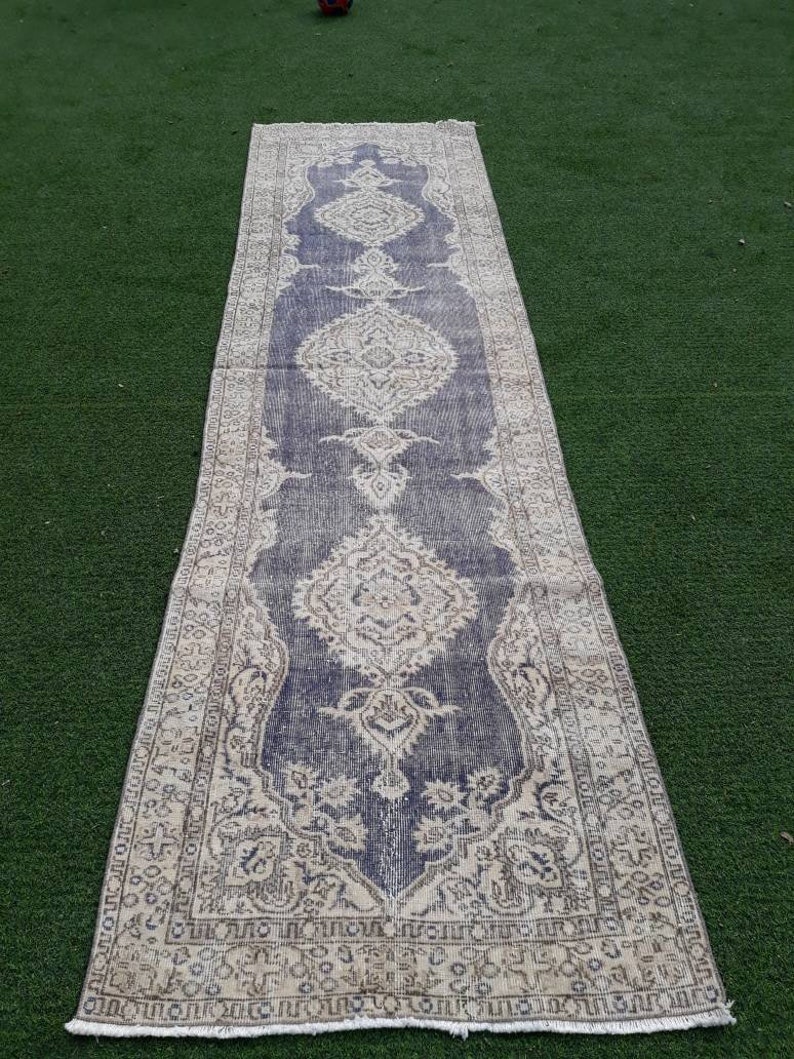 May include: A long, narrow rug with a faded blue and cream color scheme. The rug has a traditional Persian design with intricate floral patterns.