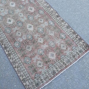 K&ouml;nnte beinhalten: Ein vintagefarbener L&auml;ufer in Rosa und Gr&uuml;n mit Fransen. Der L&auml;ufer hat ein florales Muster mit einem sich wiederholenden Design.