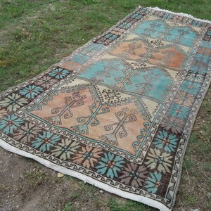 Puede incluir: Una alfombra rectangular larga con un dise&ntilde;o turco tradicional. La alfombra presenta un patr&oacute;n repetitivo de formas geom&eacute;tricas en tonos de azul, marr&oacute;n y beige.