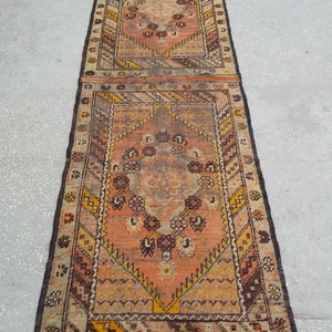 May include: A long, rectangular rug with a traditional Persian design. The rug is made of wool and has a brown, orange, and cream color scheme. The rug has a fringe on both ends.