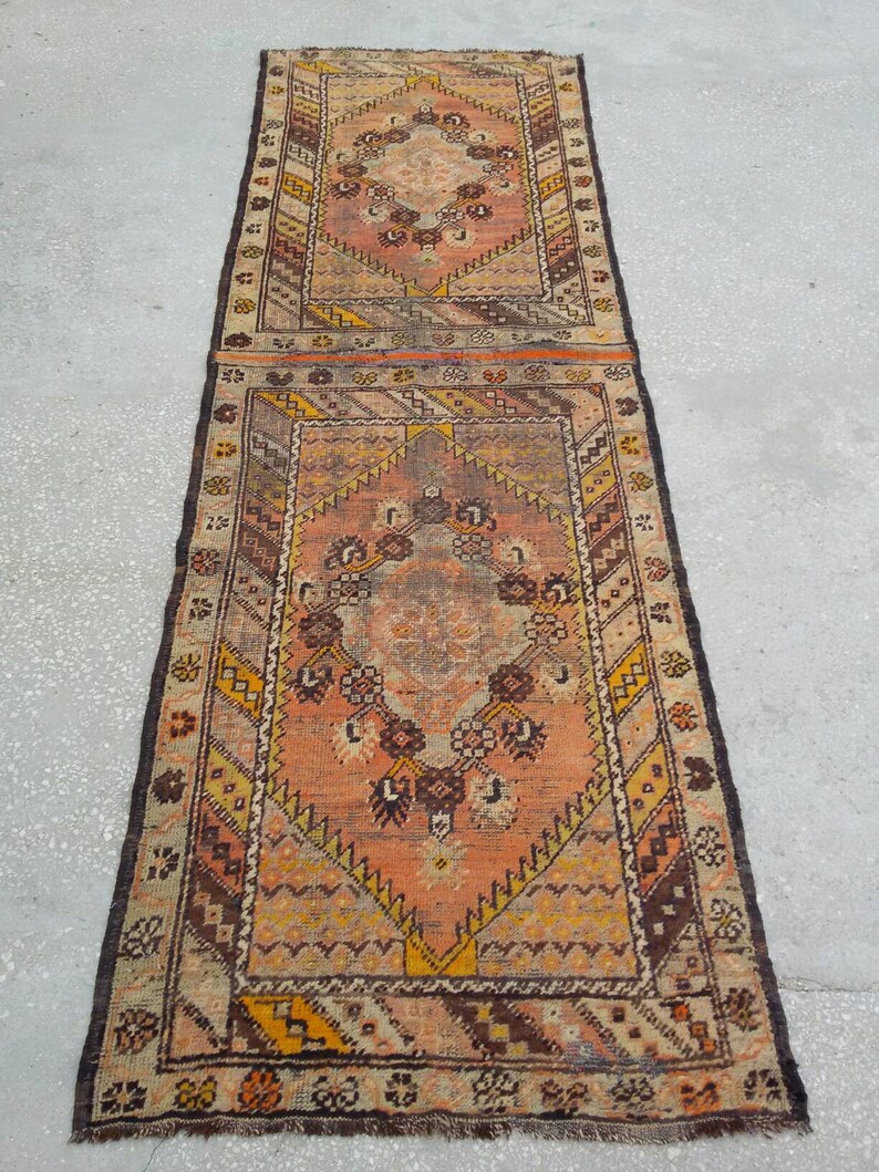 May include: A long, rectangular rug with a traditional Persian design. The rug is made of wool and has a brown, orange, and cream color scheme. The rug has a fringe on both ends.