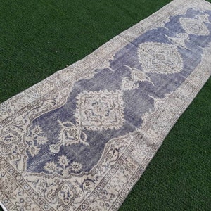 May include: A vintage runner rug with a faded blue background and intricate white and beige floral patterns. The rug has a distressed look and is perfect for adding a touch of bohemian style to any room.