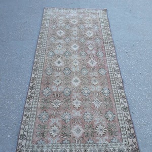 K&ouml;nnte beinhalten: Ein Vintage-L&auml;ufer mit einem rosafarbenen, wei&szlig;en und gr&uuml;nen Blumenmuster. Der Teppich hat einen abgenutzten Look und ist aus Wolle.