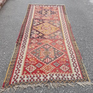 May include: A long, rectangular rug with a traditional Turkish design. The rug is woven with a variety of colors, including red, orange, yellow, blue, and green. The rug has a fringe on both ends.