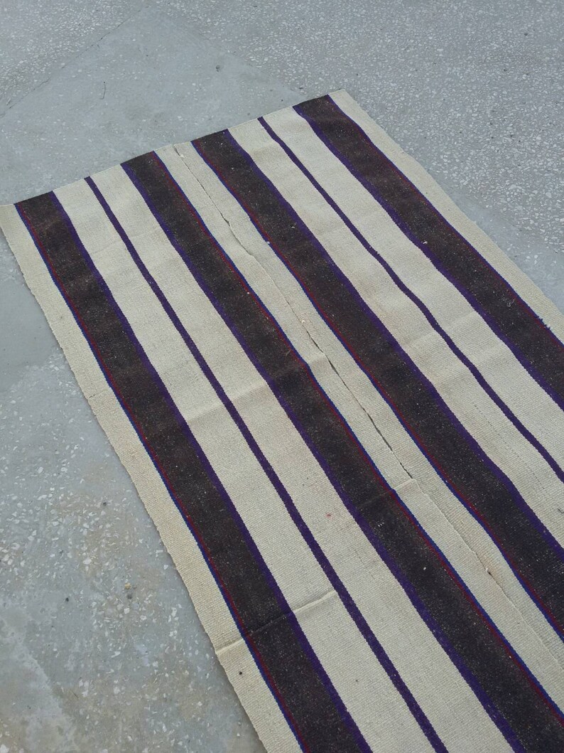 May include: A long, striped rug with alternating white and dark brown stripes. The stripes have a subtle purple and red accent.