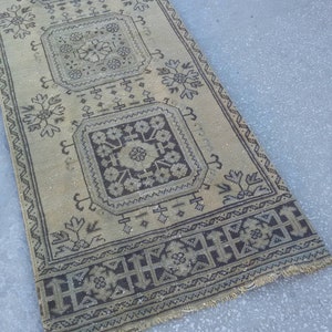 May include: A beige and brown patterned rug with a geometric design. The rug has a fringed edge and is made of a woven material.