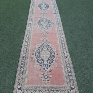 May include: A pink runner rug with a floral pattern and a black and white border. The rug has a fringed edge.