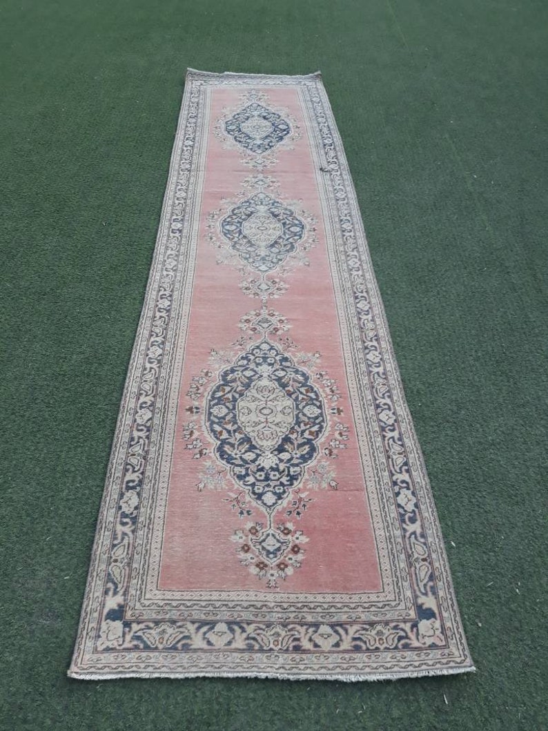 May include: A pink runner rug with a floral pattern and a black and white border. The rug has a fringed edge.