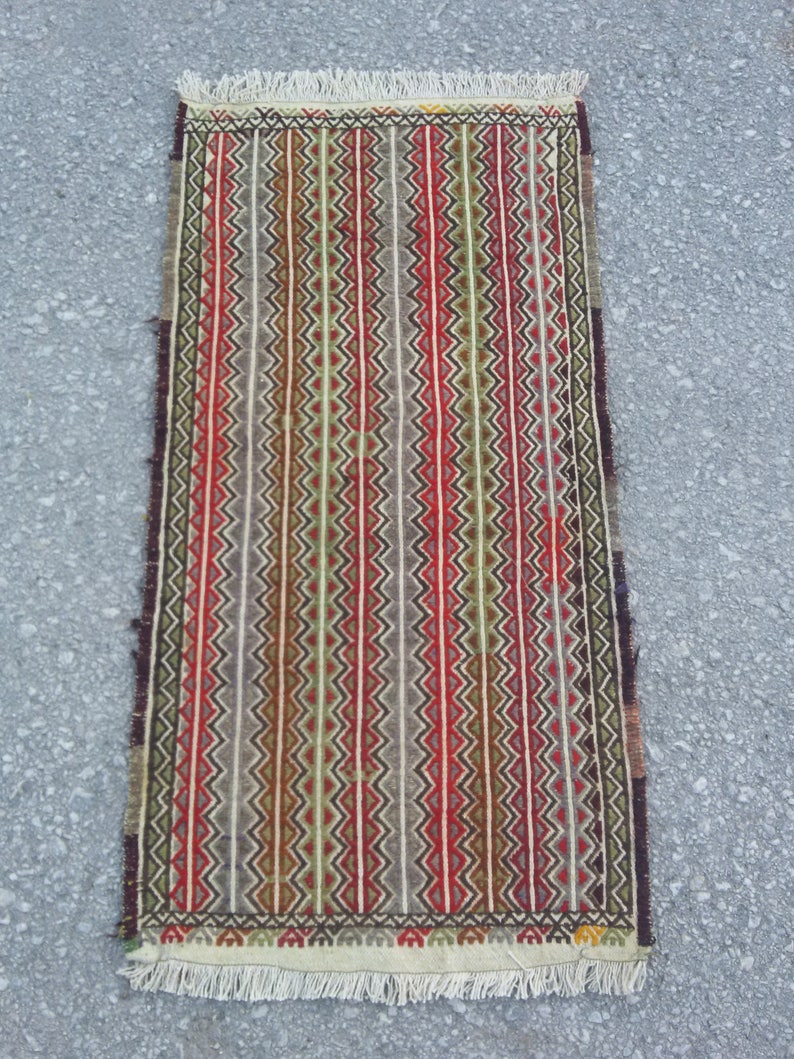 May include: A colorful striped rug with a geometric pattern. The rug has a fringe border and is made of wool.