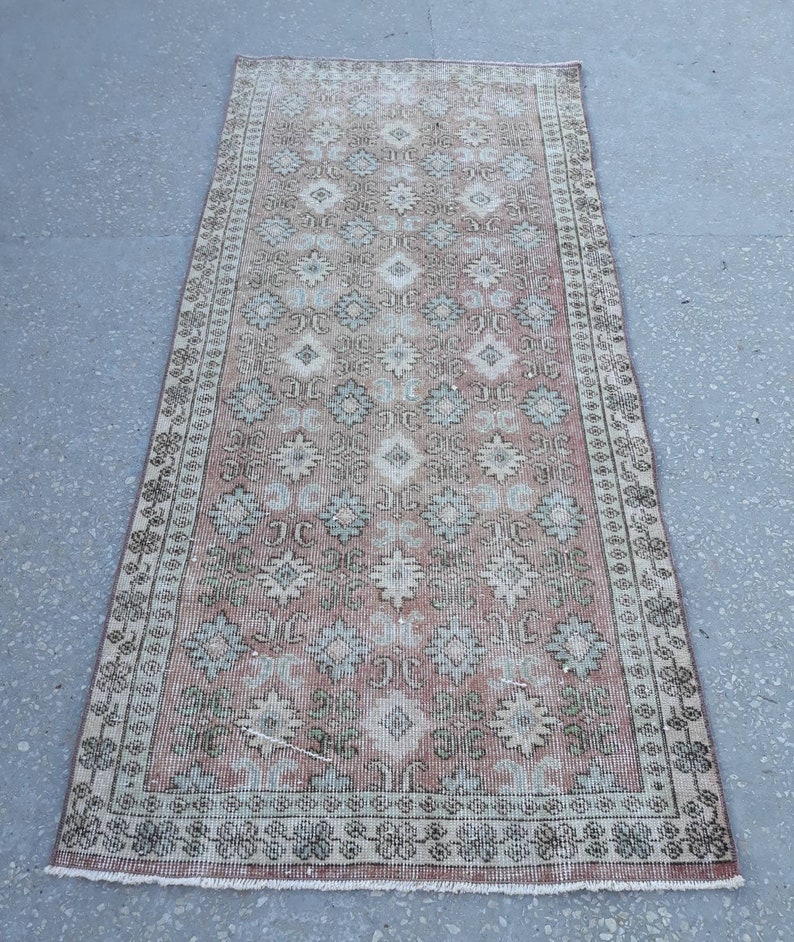 K&ouml;nnte beinhalten: Ein Vintage-L&auml;ufer mit einem geometrischen Muster in Rosa, Creme und Gr&uuml;n. Der Teppich hat einen Fransenrand und ist aus Wolle.