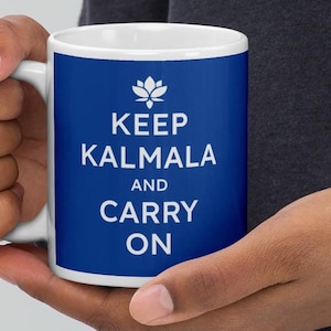 May include: White ceramic mug with a blue background and white text that reads "Keep Kalmala and Carry On". A white lotus flower symbol is above the text.