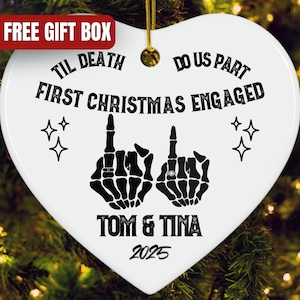 May include: White heart-shaped Christmas ornament with black text and graphics. The ornament reads "Til Death Do Us Part First Christmas Engaged" and includes skeleton hand graphics. The names "Tom & Tina" and the year "2025" are also printed on the ornament.