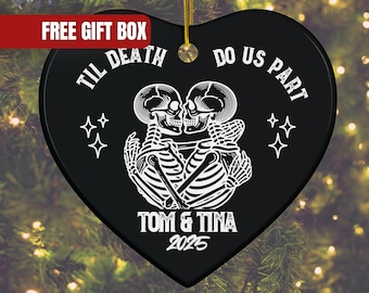 May include: Black heart-shaped ornament with a gold string for hanging. The ornament features a white illustration of two skeletons embracing, with the text "TIL DEATH DO US PART" and "TOM & TINA 2025". Four star shapes are also included.