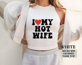 May include: White micro rib cropped tank top with the text "I ❤️ MY HOT WIFE" in black letters and a red heart. The tank top is sleeveless and has a high neckline.