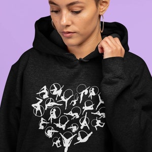 Op de afbeelding: Zwart hoodie met een witte afbeelding van een hart gemaakt van silhouetten van mensen die aerial hoop oefeningen doen.