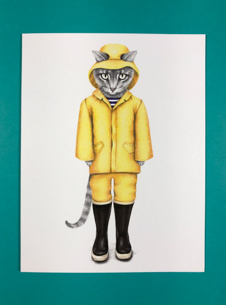Pode incluir: Um gato cinza vestindo um casaco de chuva amarelo e botas de chuva pretas. O gato est&aacute; em p&eacute; sobre um fundo branco.