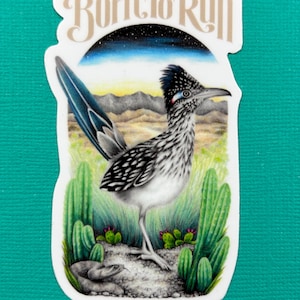 Peut inclure: Un autocollant représentant un grand géocoucou dans un paysage désertique avec des cactus et un serpent. Le texte "Born to Run" est inscrit en haut dans une police stylisée. L'illustration est détaillée.
