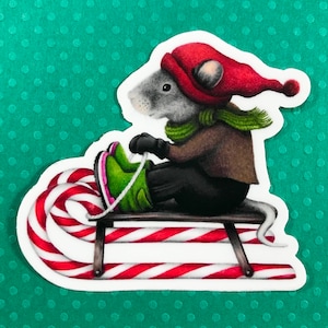 May include: A gray mouse wearing a red hat and green scarf is riding a candy cane sled. The sled is made of wood and has a red and white candy cane design.