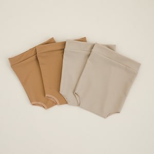 May include: Three pairs of cotton shorts in beige and brown colors. The shorts are folded and arranged in a row on a white background.