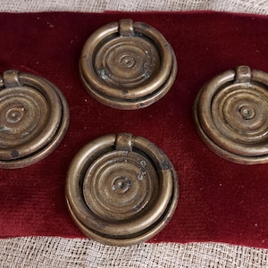 Puede incluir: Cuatro tiradores de cajón de latón antiguo con un asa de anillo y un diseño de círculos concéntricos.