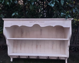 May include: White wooden wall shelf with two shelves and four hooks. The shelf has a decorative design on the top edge and a distressed white paint finish.