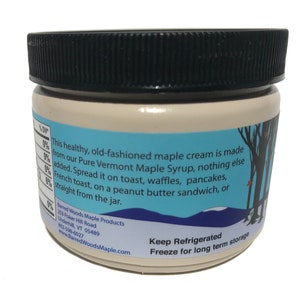 K&ouml;nnte beinhalten: Ein wei&szlig;es Glas mit schwarzem Deckel, gef&uuml;llt mit Ahorncreme. Das Etikett lautet "This healthy, old-fashioned maple cream is made from our Pure Vermont Maple Syrup, nothing else added. Spread it on toast, waffles, pancakes, French toast, on a peanut butter sandwich, or straight from the jar." Das Etikett enth&auml;lt auch den Firmennamen und die Kontaktinformationen. Das Glas steht auf einer wei&szlig;en Oberfl&auml;che.