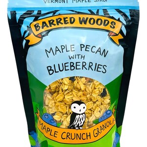 Puede incluir: Una bolsa azul y verde de granola Barred Woods Maple Pecan con ar&aacute;ndanos y jarabe de arce. La bolsa presenta una ilustraci&oacute;n de un b&uacute;ho y ar&aacute;ndanos. La bolsa es de 10 oz (284 g).