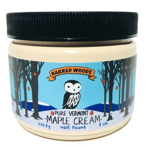Może przedstawiać: Biały słoik z czarną pokrywką i etykietą z napisem "Barred Woods Pure Vermont Maple Cream. Half Pound 8 oz. 226.8g". Etykieta przedstawia kresk&oacute;wkową sowę i zimową scenę z drzewami i śniegiem.