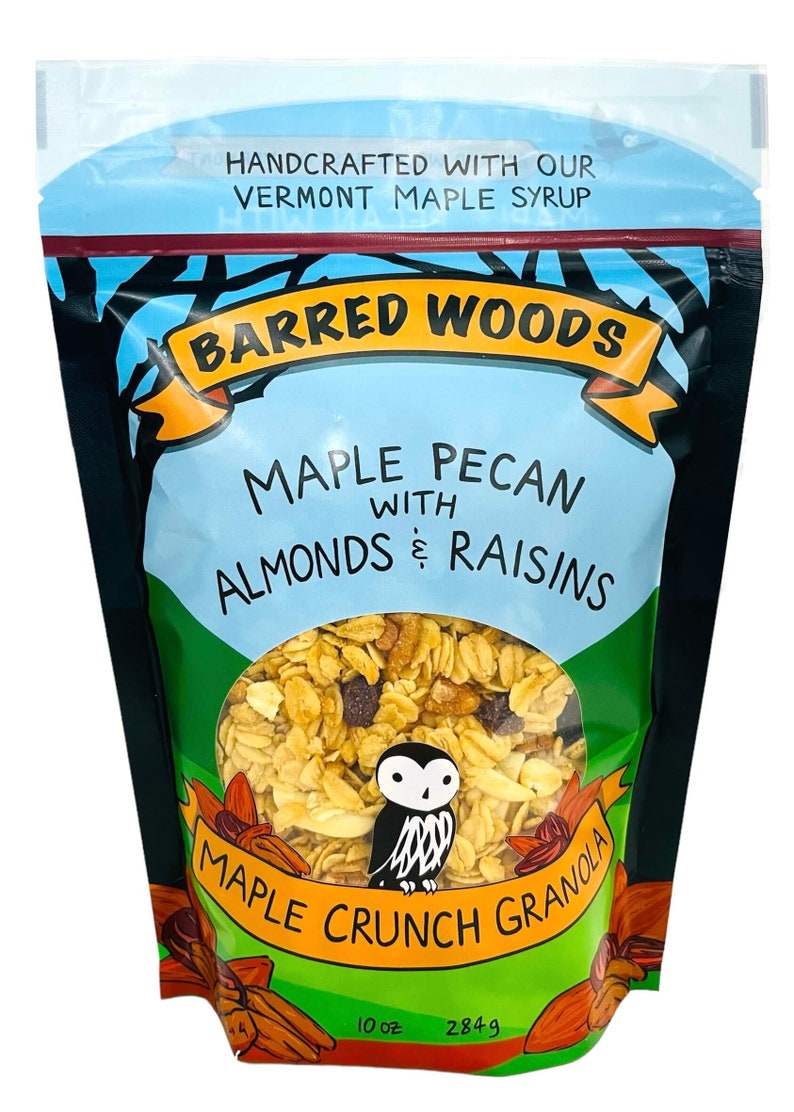 Puede incluir: Una bolsa de 284 g de granola Barred Woods Maple Crunch Granola con pecanas, almendras y pasas. La bolsa es negra con una etiqueta azul y amarilla que presenta un b&uacute;ho de dibujos animados. La granola es visible a trav&eacute;s de una ventana transparente en la bolsa.