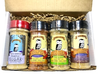 May include: A set of four 5 oz jars of maple sugar seasoning blends. The jars are labeled with the Barred Woods logo, a cartoon owl, and the flavor of each blend: Maple Sugar, Maple Sugar Chipotle Rub, Maple Sugar Garlic & Pepper, and Maple Sugar Cinnamon. Each jar is handcrafted with pure Vermont maple syrup.