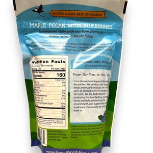 Puede incluir: Una bolsa azul y blanca de granola de pacana con ar&aacute;ndanos. La bolsa tiene una etiqueta de informaci&oacute;n nutricional y una descripci&oacute;n del producto. El producto est&aacute; endulzado con jarabe de arce puro de Vermont y az&uacute;car de arce. La bolsa se fabrica en una instalaci&oacute;n donde se pueden procesar pescado, mariscos, frutos secos, cacahuetes, soja y leche.