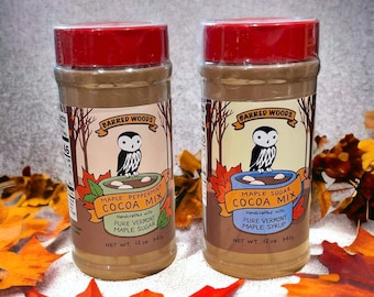 May include: Two 12-ounce jars of Barred Woods cocoa mix. The jar on the left is labeled "Maple Peppermint Cocoa Mix" and the jar on the right is labeled "Maple Sugar Cocoa Mix". Both jars feature an owl illustration and are handcrafted with pure Vermont maple syrup or sugar.