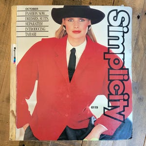 May include: A vintage Simplicity pattern book cover featuring a woman in a red blazer, black hat, and tie. The cover text includes "October", "Fashion Now...", and "Introducing Tahari". The Simplicity logo is in white on the right side.