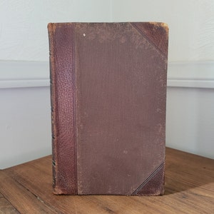 May include: A brown leather-bound book with gold accents and a textured cover.