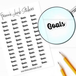 May include: A sheet of white paper with black text that reads "Freannie Lamb Stickers" and "Goals" repeated multiple times. The sheet is on a white surface with two yellow pencils.