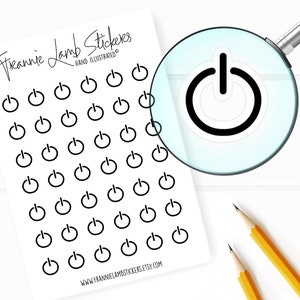 以下が含まれることがあります： 白紙に、黒と白の電源ボタンのステッカーが36個貼られています。ステッカーはグリッド状に配置されています。シートの上部には「Frannie Lamb Stickers」と「Hand Illustrated」の文字が印刷されています。