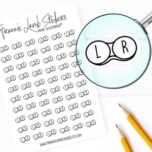 May include: A sheet of contact paper stickers with 50 black and white contact lens stickers that say "L" and "R" on them. The stickers are arranged in rows and columns. The sheet is white with the text "Freannie Lamb Stickers" and "HAND ILLUSTRATED" at the top.