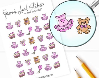 May include: A sheet of pink and white stickers featuring a variety of baby-themed illustrations, including a pink dress, a teddy bear, a train, and blocks. The text "Freannie Lamb Stickers" and "HAND ILLUSTRATED" is printed at the top of the sheet.