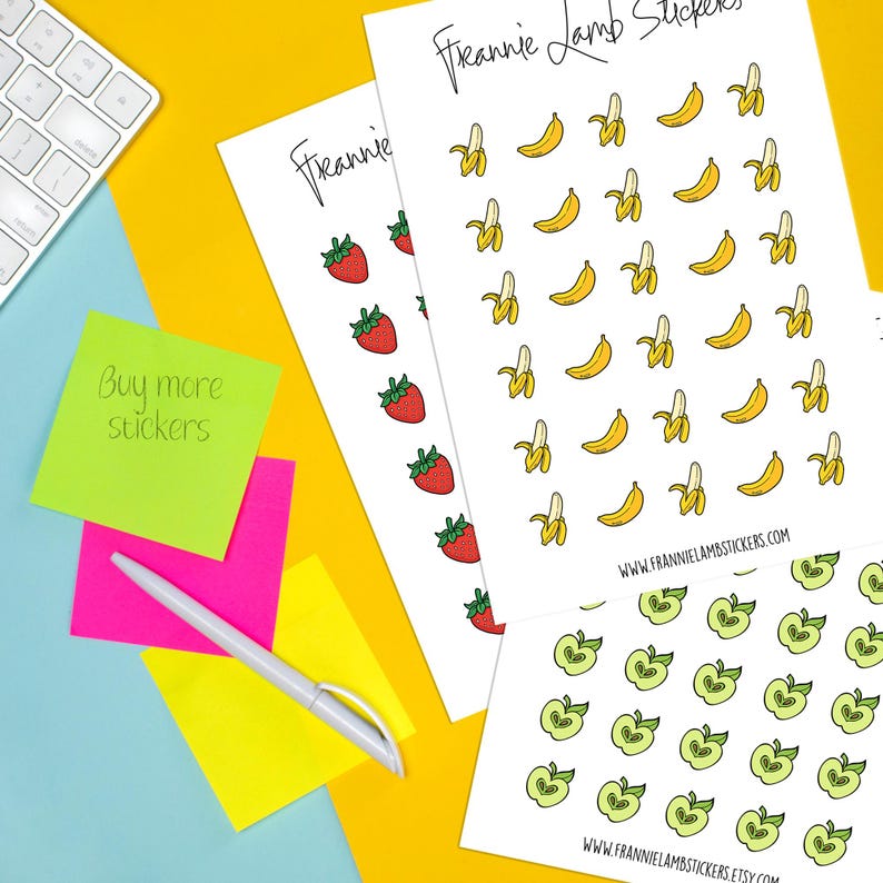 K&ouml;nnte beinhalten: Bl&auml;tter mit Aufklebern mit Illustrationen von Erdbeeren, Bananen und &Auml;pfeln. Die Aufkleber befinden sich auf wei&szlig;em Papier, mit dem Markennamen "Frannie Lamb Stickers" oben und unten. Ein Stift und Haftnotizen sind ebenfalls im Bild.