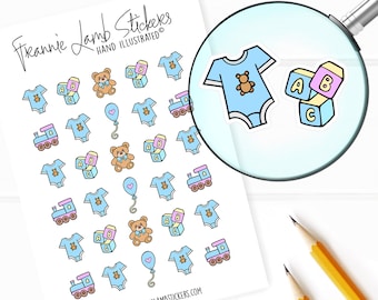 May include: A sheet of stickers featuring baby-themed illustrations. The stickers include a blue onesie, a teddy bear, a train, and blocks that spell out "ABC". The text "Freannie Lamb Stickers Hand Illustrated" is at the top of the sheet.