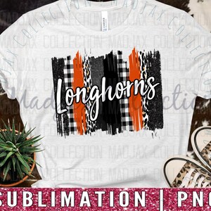 May include: A white short-sleeve t-shirt featuring a central graphic with the word Longhorns in white script. The design includes vertical stripes of orange, black, white buffalo plaid, and leopard print patterns on a textured brushstroke background.