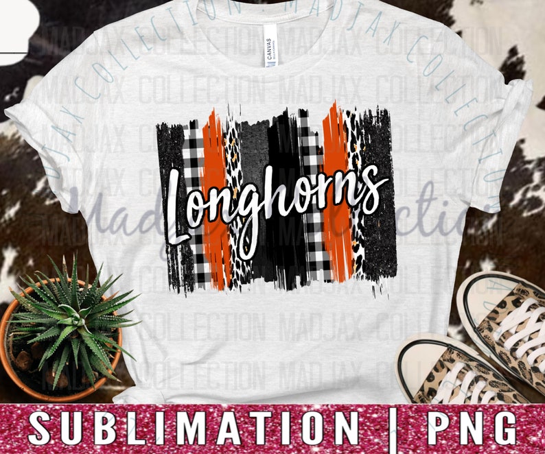 May include: A white short-sleeve t-shirt featuring a central graphic with the word Longhorns in white script. The design includes vertical stripes of orange, black, white buffalo plaid, and leopard print patterns on a textured brushstroke background.