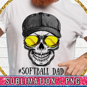May include: A sublimation design featuring a skull wearing a black baseball cap and sunglasses with a softball inside each lens. The text '#SOFTBALL DAD' is below the skull. The design is on a white t-shirt.
