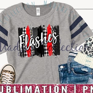 May include: Gray t-shirt with navy blue stripes on the sleeves. The shirt features the word "Flashes" in white, with a design of red, black, and leopard print brushstrokes. A leopard print beanie, denim shorts, and leopard print sneakers are also visible.