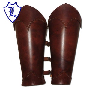 Puede incluir: Un par de protectores de brazo de cuero marrón con correas y costuras decorativas.