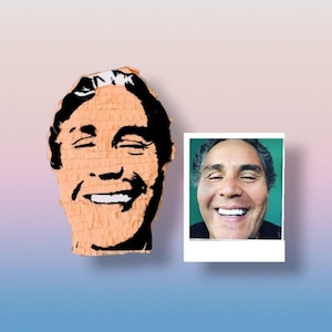 May include: A peach-colored pi&ntilde;ata shaped like a human head with black graphic facial features and a smiling expression, displayed alongside a square photograph of a person with a similar smiling face against a solid green background.