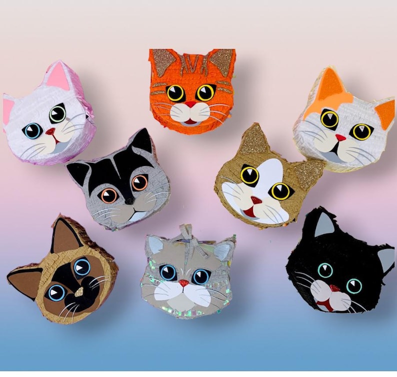 May include: A collection of colorful cat-shaped pi&ntilde;atas. Each pi&ntilde;ata features a unique design with different colors, including orange, gray, white, and black. The cat faces have large eyes, whiskers, and red mouths. Some have glitter accents.