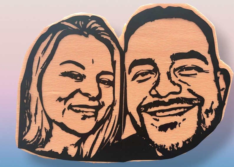May include: A custom wooden plaque featuring a laser-cut or engraved black line art portrait of two people side-by-side. The light-colored wood grain is visible throughout the background, while the facial features are defined by bold black lines.