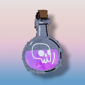 Puede incluir: Una piñata gris en forma de botella con una calavera y la palabra "veneno" en blanco. La botella tiene un diseño de líquido púrpura y un corcho marrón. La piñata está diseñada para parecerse a una botella de poción.